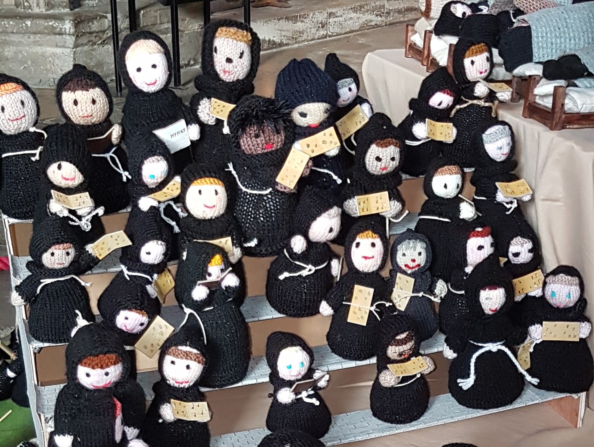 Knitted monks with hymn sheets singing in a choir.